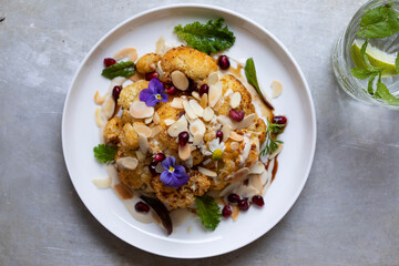 Roast cauliflower with almond flakes, pomegranate and tahini sauce
