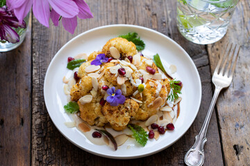 Roast cauliflower with almond flakes, pomegranate and tahini sauce