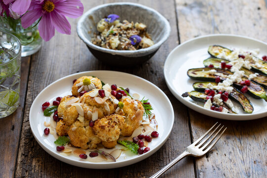 Vegan Dishes Of Miso Aubergine, Roasted Cauliflower And Baby Courgettes