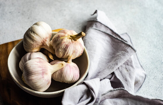 Bowl of fresh cloves of garlic and garlic bulbs on a table