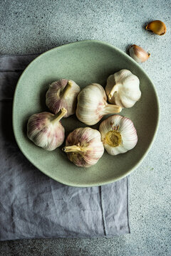 Bowl of fresh cloves of garlic and garlic bulbs on a table