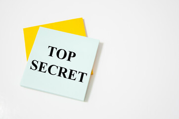 Top Secret text written on a white notepad with colored pencils and a yellow background. word