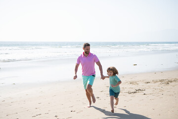 father and son running on summer beach. family travel weekend and vacation.