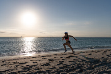 Fototapeta na wymiar Active woman runner in sportswear run on beach sand along seaside, running