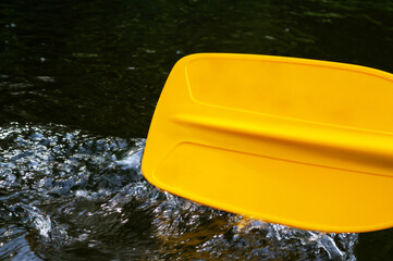 The kayaking paddle touches the water and creates splashes and ripples on the water