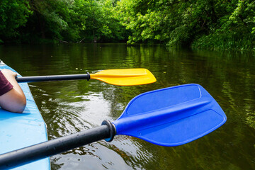 Paddle for rowing blue and yellow flowers in the hands of people while kayaking on the river