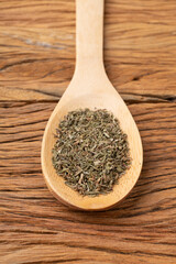 Closeup of dried thyme on a spoon over wooden table