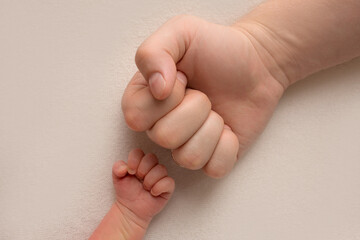 Dad and newborn boy son keep their hands in a fist, small and big fists. Father and son, the first boxing punch.