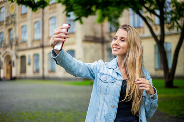 Young beautiful fashionable girl in a denim jacket makes a selfie on the phone