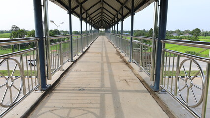 Pedestrian footpath on the bridge over the road. Concrete footpath with roof for pedestrians to cross the highway for safety. Selective focus