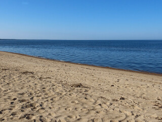 Baltic sea and sandy beach: blue sky and sea, white waves, yellow sand as copy space