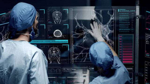 Professional doctors analyzing patient's medical MRI diagnosis by checking on a large glass screen with futuristic holograms. Concept of: medicine, doctors, future, holographic, brain scan