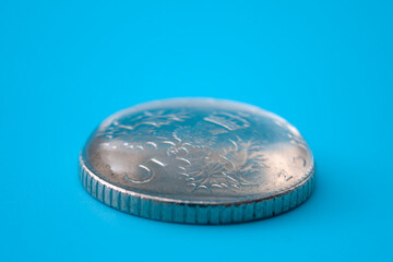 Scientific demonstration and surface tension concept with water on metal coin isolated on blue...