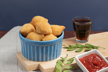 Coxinha of chicken served with soda and ketchup.