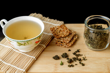 Cup with green herbal tea and dried ivan tea leaves on the table