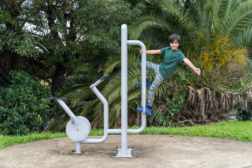 Fototapeta na wymiar Young boy gym equipment. Fit Indian child playing with gym machine at park.