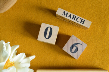 March 6, Wooden Calendar cube on yellow felt fabric with peony flower for date icon background.	