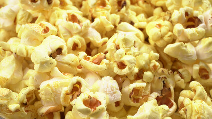 Heap of delicious popcorn. Scattered popcorn texture background. Selective focus. Salt popcorn on the wooden table.