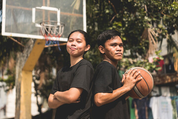 Two young Filipino friends after a street basketball game at a local court. - obrazy, fototapety, plakaty