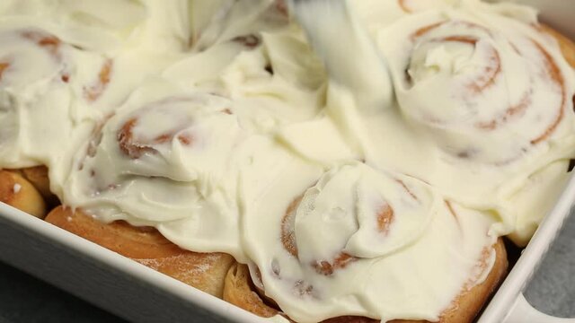 Spreading frosting on cinnamon rolls freshly baked homemade