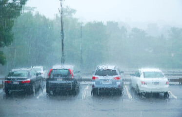 vehicles in parking lot in summer thunderstorm with heavy rain