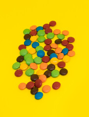 A lot of colorful chocolate lentils isolated on absolute yellow background