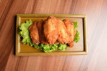 deep fried crispy chicken wings on lettuce and bamboo plate wood table asian snack halal menu fast food cuisine