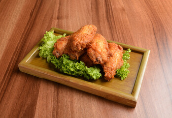 deep fried crispy chicken wings on lettuce and bamboo plate wood table asian snack halal menu fast food cuisine