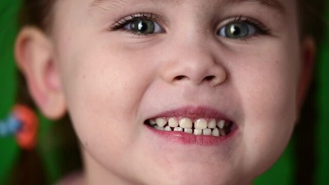Time-lapse of a beautiful girl, little girl on a green background close up.