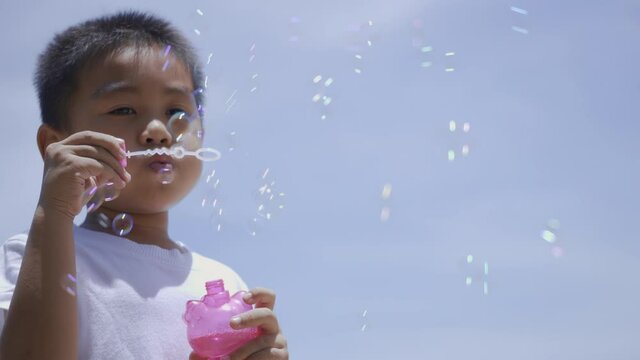 Happy little child boy blowing soap bubble, Funny kid blow many bubbles outdoor at the beach on summer day