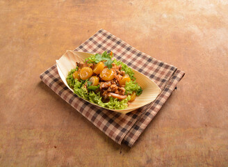 asian hakka traditional cuisine snack menu stir fried abacus ball with minced meat and mushroom in small paper bowl on wood table (suan pan zi)