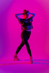 Fototapeta premium Beautiful female dancer wearing black and high heels while performing pole dance tricks