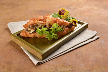 asian stir fried assorted mushroom and vegetables in freshly baked croissant on bamboo plate and...