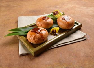 three mini kong bak bao chinese braised pork belly with baked small fresh bread bun on panda leaf...