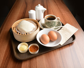 asian local traditional breakfast set halal menu with half boiled egg, baked roti mantou bun with butter and kaya jam and hot kopi coffee drink cuisine