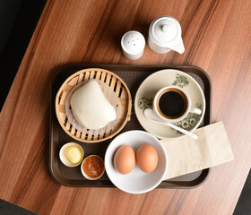 asian local traditional breakfast set halal menu with half boiled egg, baked roti mantou bun with butter and kaya jam and hot kopi coffee drink cuisine