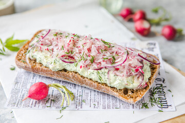 Fresh green spring sandwich with cream cheese and radish at light background. Copyspace