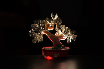Chinese money tree statuette on a black background illuminated from behind by light