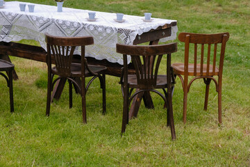Wooden chairs at the tea table on the lawn before the rain. Selective focus. Vintage tea party scene. Ukraine. 