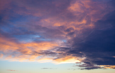 Colorful sunset or sunrise in the sky. The sky and clouds are painted in different bright orange, yellow and blue colors.