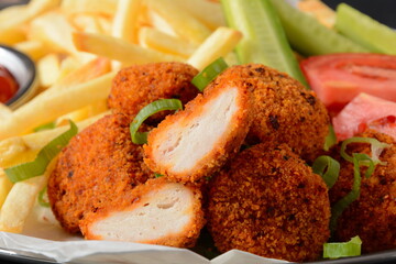 Chicken breast nuggets with popular sauce and chips and vegetables for choice on silver tray
