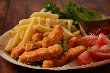 Chicken breast nuggets with popular sauce and chips and vegetables for choice on wooden background