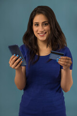 Portrait of a young woman holding a mobile and a credit card.