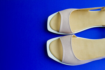 women's shoes of beige color on a blue background. the shoes are removed from the top