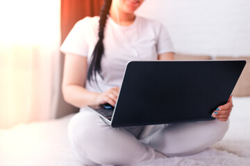 Naklejka premium The concept of a working house is a girl sitting on a bed with a laptop and business reports, close-up