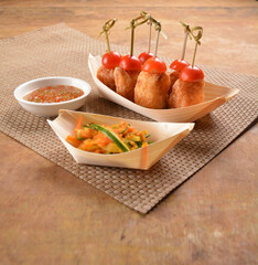 deep fried shrimp paste roll (wu Xiang) with achar and spicy sauce in bento box on wood table asian snack halal menu