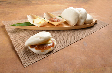 steamed bun (man tou) with kaya and butter jam on pandan leaf board wood table asian bread halal menu