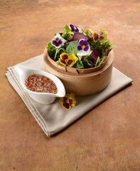 beautiful flower vegetables salad in bamboo basket with homemade salad dressing sauce on wood table asian vegan halal menu