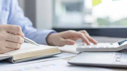 Head of accounting is recording the company's financial growth statistics using graphs as a reference for reviewing and analyzing the results, Taking notes and analyzing data graphs in office.