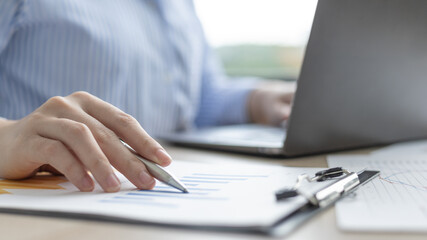 Fototapeta premium Asian business women are analyzing graphs, financial statistics and calculating corporate returns in private offices, Market research reports and income statistics, Financial and Accounting concept.
